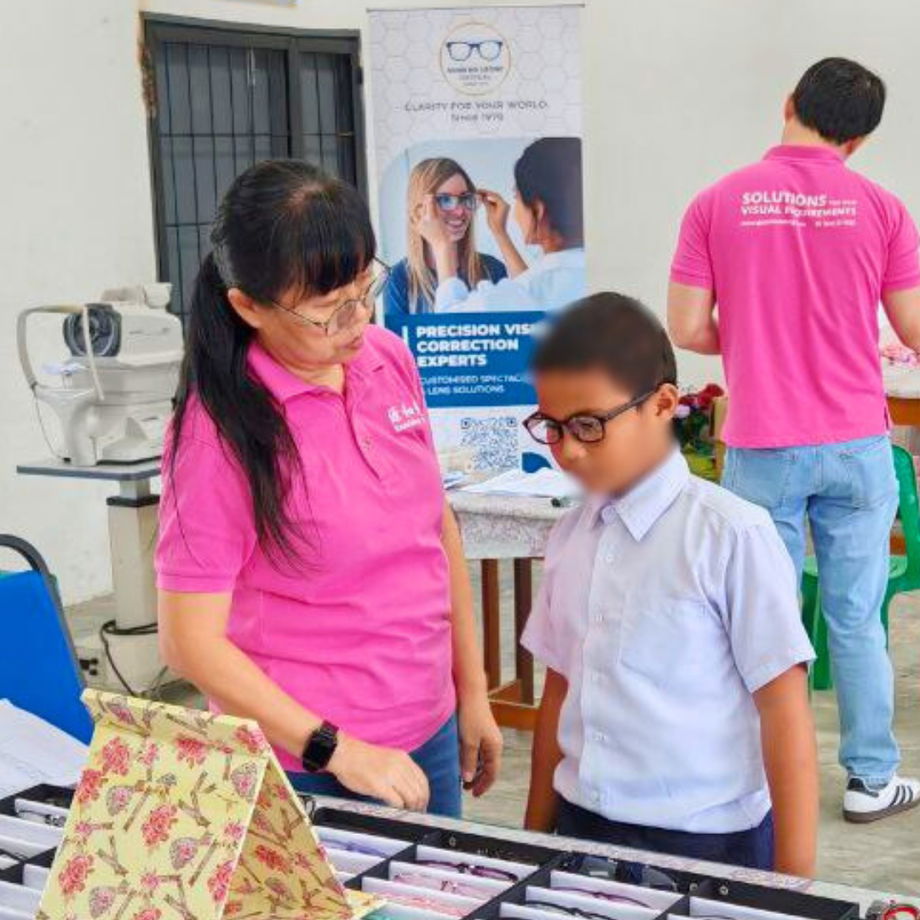 Student trying on different spectacle frames with assistance from GHL VisionFirst team