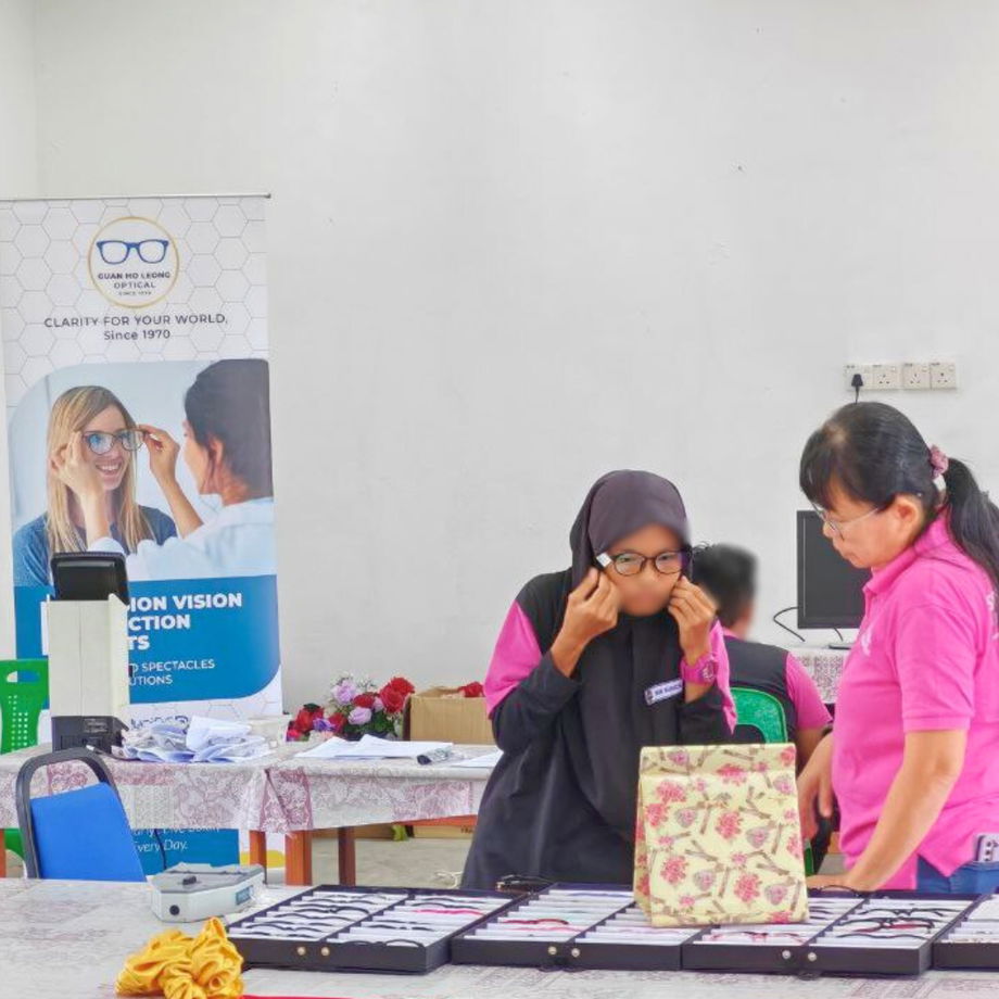 Student trying on different spectacle frames with assistance from GHL VisionFirst team