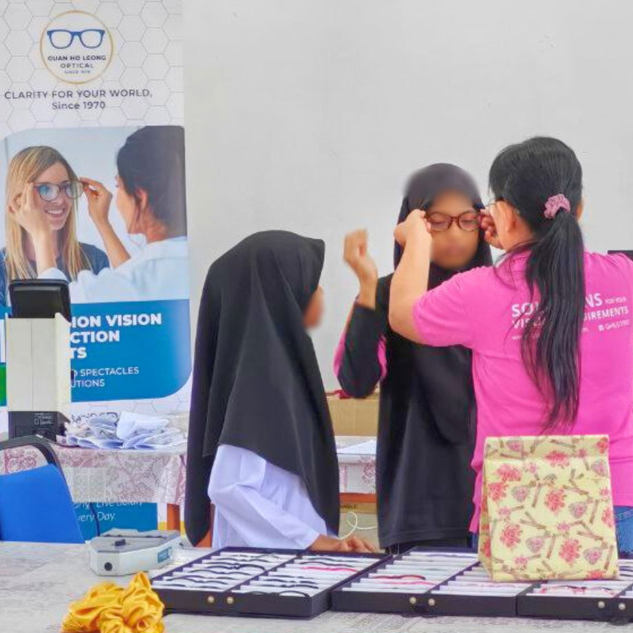 Student trying on different spectacle frames with assistance from GHL VisionFirst team