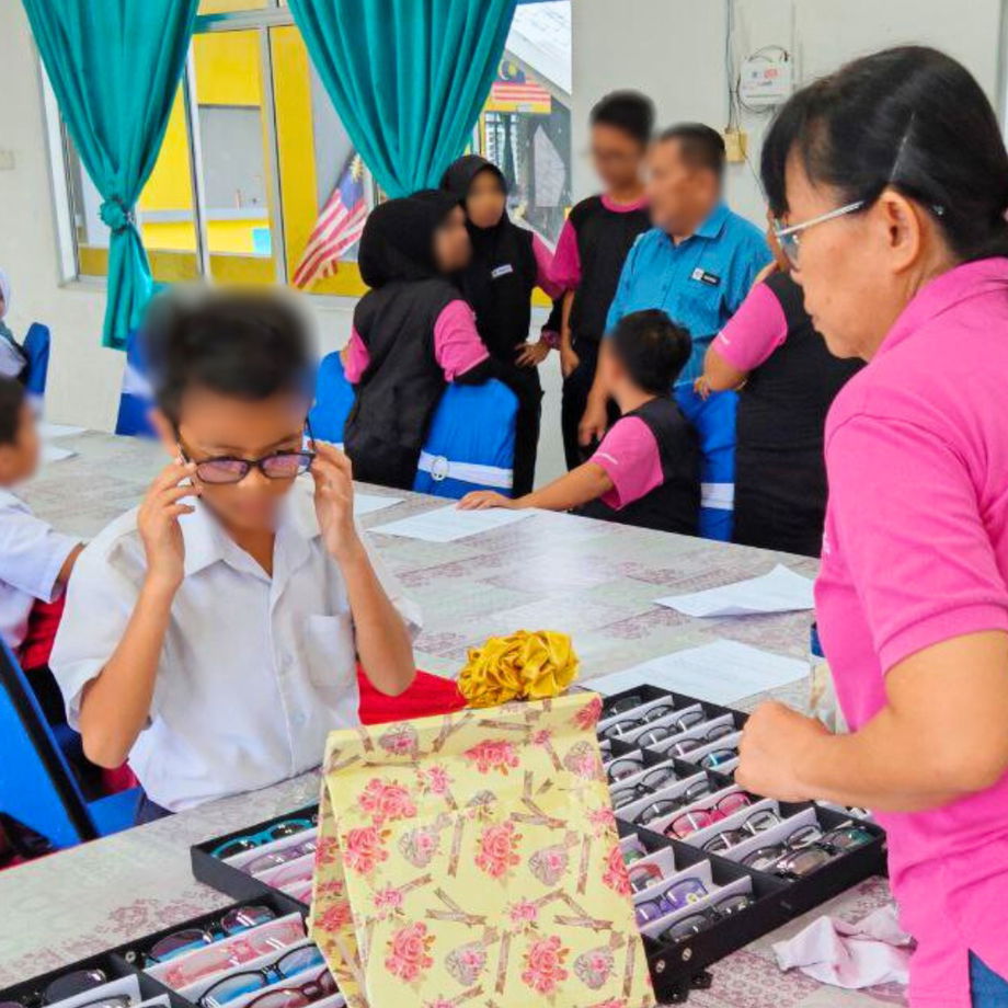 Student trying on different spectacle frames with assistance from GHL VisionFirst team